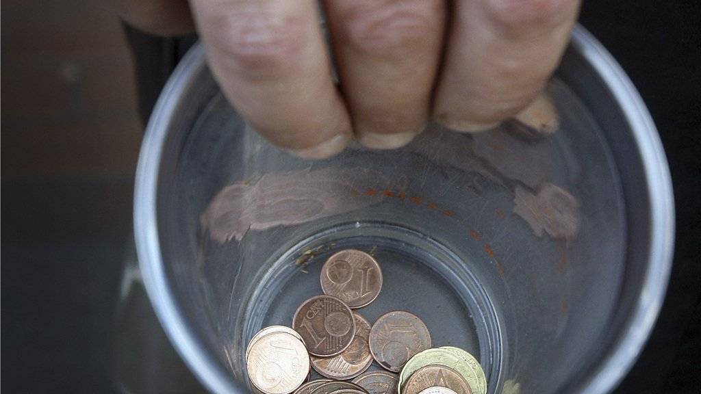 Ein Bettler hält in Düsseldorf einen Becher mit Kleingeld. (Symbolbild)