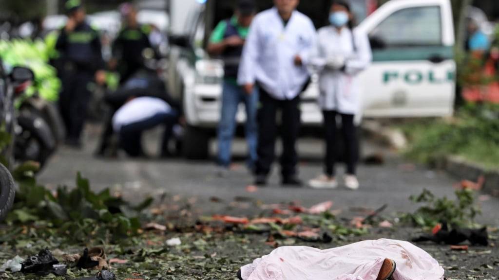 Nach einer Bombenexplosion liegt eine Leiche auf der Straße, bedeckt mit einem Laken. Laut lokalen Medienberichten explodierten drei Sprengsätze, mindestens zwei Menschen kamen dabei ums Leben. Foto: Santiago Saldarriaga/AP/dpa