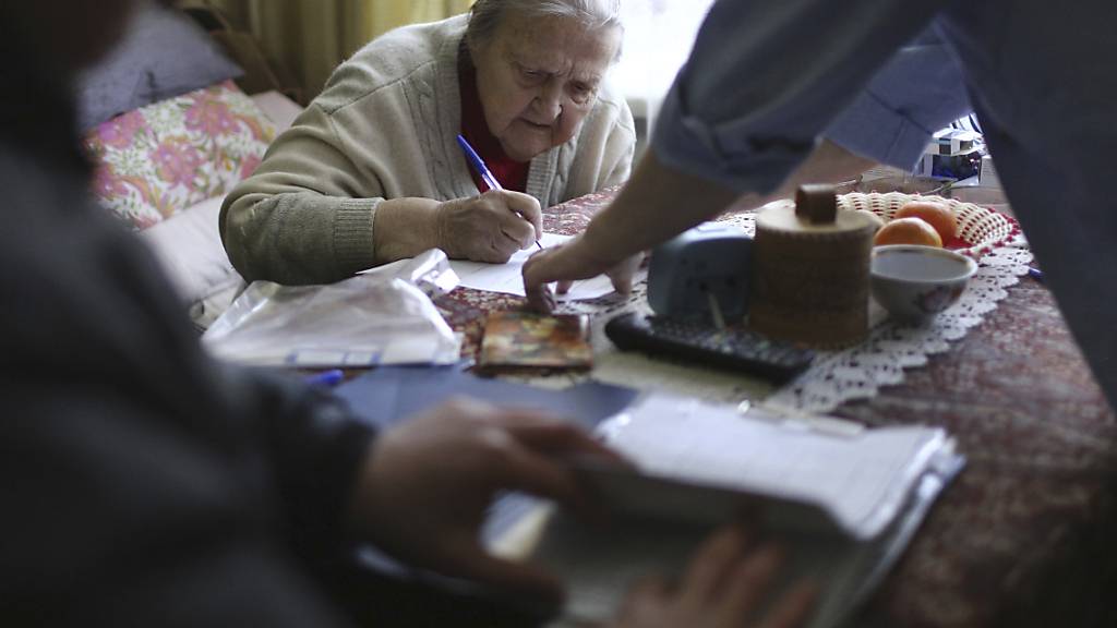 Eine Frau füllt ihren Stimmzettel für die Präsidentenwahl aus, während sie von einem mobilen Wahlkomitee besucht wird. Foto: Uncredited/AP/dpa