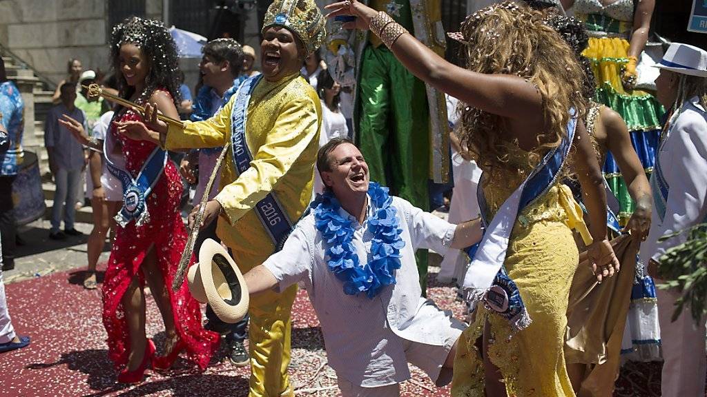 Nach der Schlüsselübergabe kniet Rios Stadtpräsident Eduardo Paes vor einer tanzenden Karnevals-Prinzessin. Links von Paes ist «König Momo» mit dem Schlüssel.