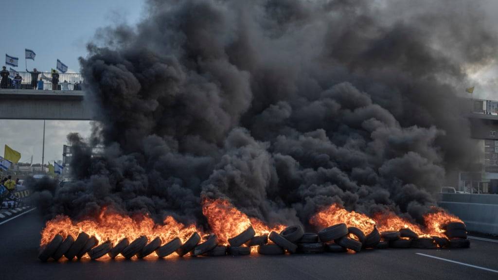 dpatopbilder - Israelische Demonstranten blockieren mit brennenden Reifen die Hauptverkehrsstraße in Zentralisrael und fordern die sofortige Freilassung der Geiseln und ein Ende des Krieges. Foto: Ilia  Yefimovich/dpa