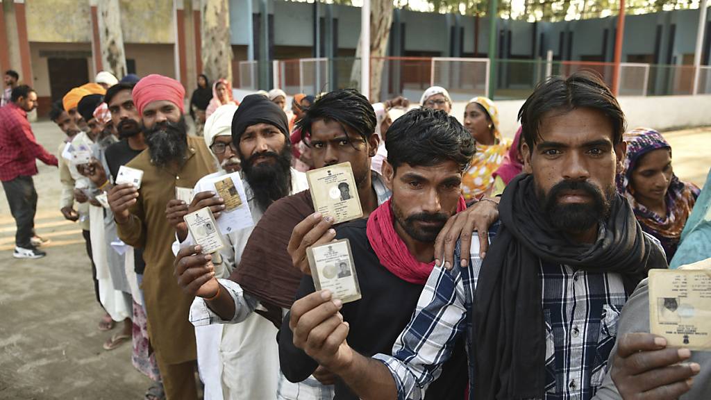 Menschen zeigen ihre Wahlkarten, während sie während der siebten und letzten Phase der Parlamentswahl in der Nähe von Amritsar in einer Schlange stehen, um ihre Stimme abzugeben. Foto: Prabhjot Gill/AP/dpa