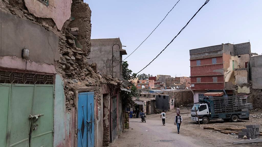 Menschen gehen in der Stadt Amizmiz außerhalb von Marrakesch, Marokko, an Gebäuden vorbei, die von dem Erdbeben im September 2023 betroffen waren. Foto: Mosa'ab Elshamy/AP/dpa