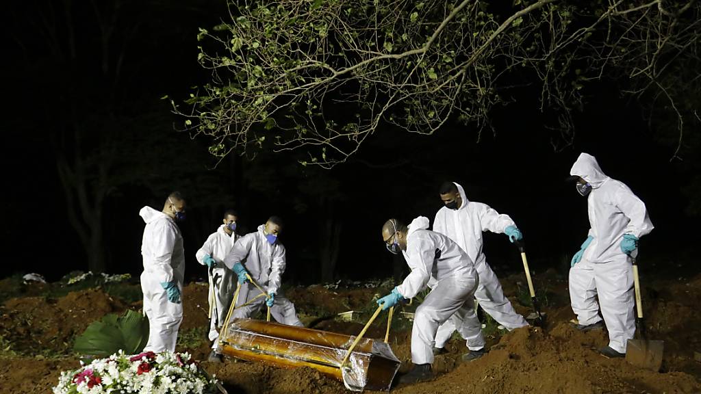 Friedhofsarbeiter senken den Sarg eines Covid-19-Opfers in sein Grab auf dem Friedhof Vila Formosa. Foto: Nelson Antoine/AP/dpa