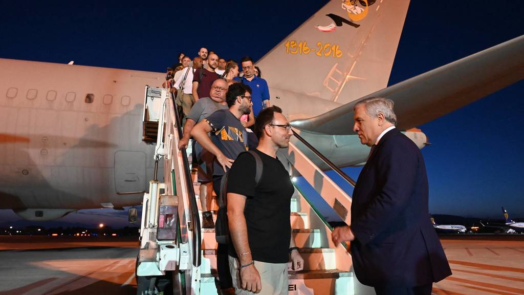 Tajani (R) begrüsst Passagiere eines Flugzeugs, das aus Niger abgeflogen ist, auf dem Flughafen in Rom. An Bord des Sonderflugs waren Italiener, die beschlossen hatten, Niger nach dem Putsch zu verlassen.