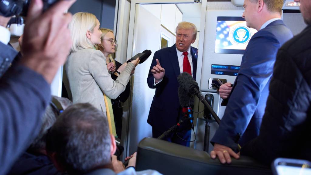 ARCHIV - US-Präsident Donald Trump (M) spricht mit Reportern an Bord der Air Force One. Foto: Evan Vucci/AP/dpa