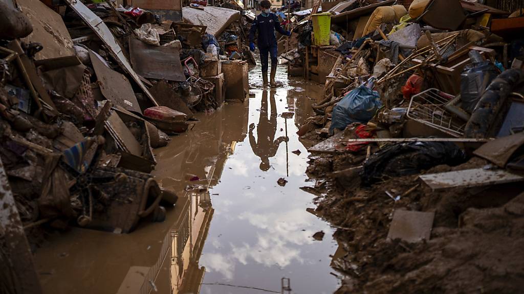 Eine Person geht durch eine mit Schlamm bedeckte Straße in Paiporta, Valencia, Spanien. Foto: Emilio Morenatti/AP/dpa