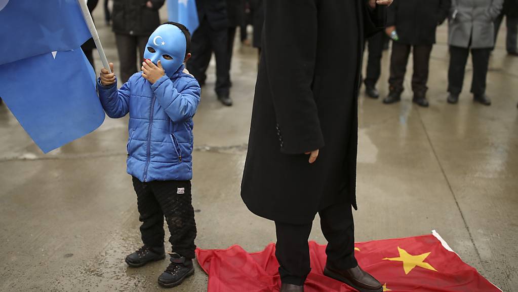 Auf der chinesischen Fahne stehend protestiert ein Demonstrant in Istanbul gegen den Besuch des chinesischen Außenministers Wang in der Türkei. Foto: Emrah Gurel/AP/dpa