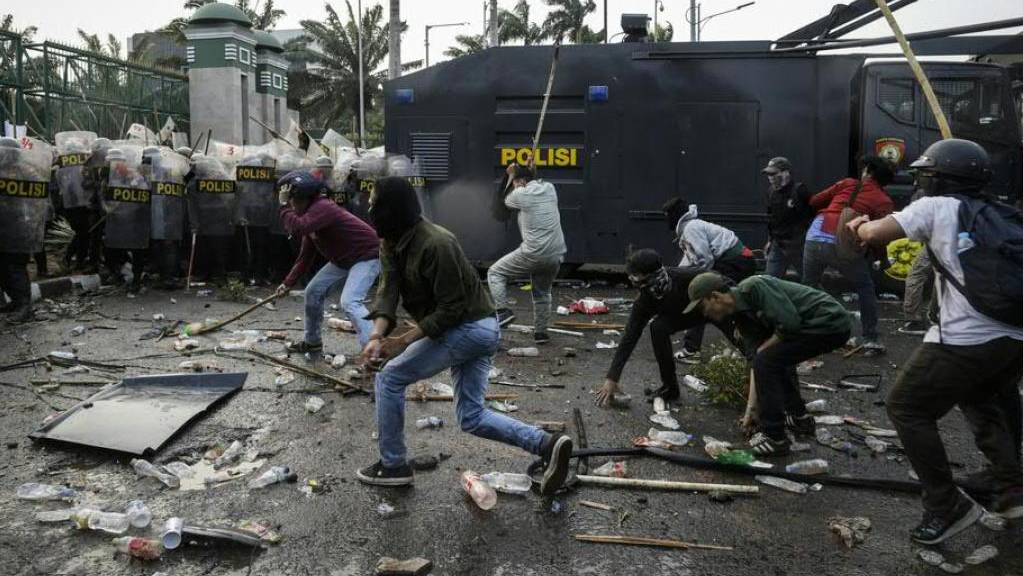 Demonstranten in Jakarta attackieren Polizisten mit Steinen und Stöcken.