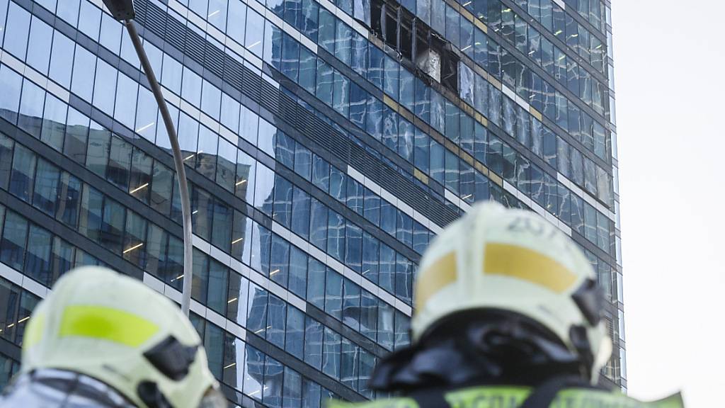 Feuerwehrleute stehen neben einem beschädigten Gebäude im Geschäftsviertel «Moscow City» nach einem gemeldeten Drohnenangriff. Die russische Hauptstadt ist nach Angaben von Bürgermeister Sobjanin erneut Ziel eines feindlichen Drohnenangriffs geworden. Foto: Uncredited/AP/dpa