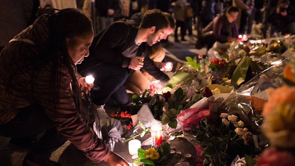 FILED - A woman lays a candle on Rue Alibert. In a coordinated series of attacks, extremists of the Islamic State (IS) killed 130 people. Photo: picture alliance / dpa