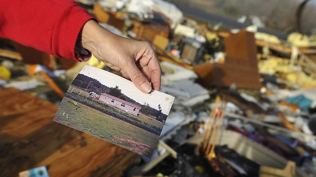 Vor den Trümmern eines Hauses in Lutts, Tennessee, zeigt eine Frau ein Foto des Gebäudes vor dem Durchzug des Tornados.