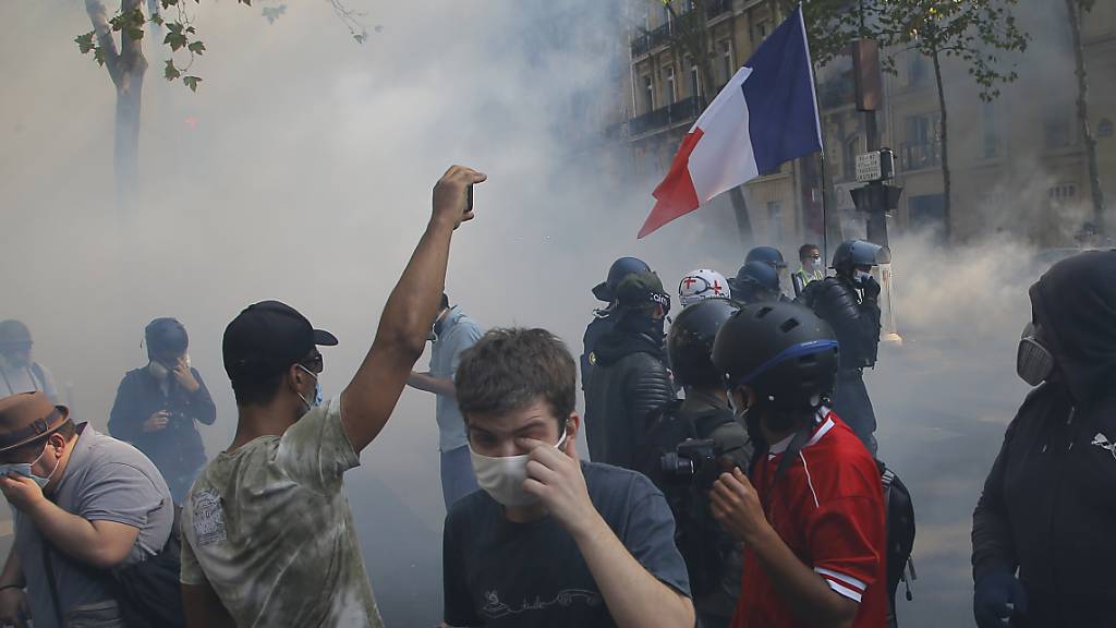 «Gelbwesten»-Demonstranten gehen in Paris vor Tränengas in Deckung. Foto: Michel Euler/AP/dpa