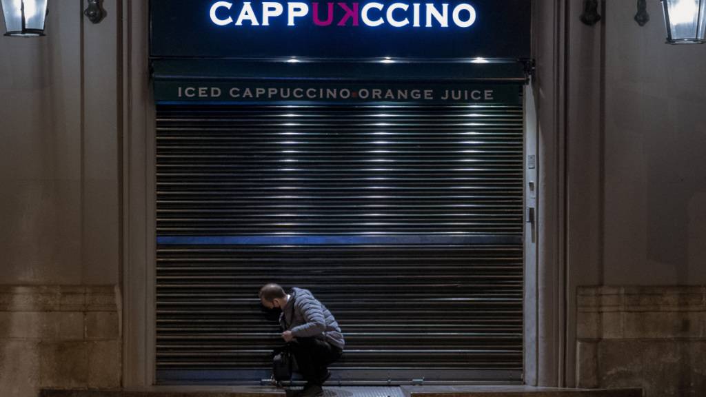 dpatopbilder - Ein Angestellter schließt ein Café vor der Sperrstunde in Barcelona. Foto: Emilio Morenatti/AP/dpa