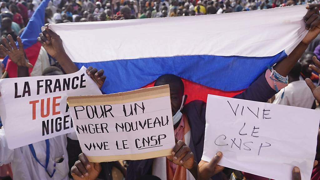 Teilnehmende des Marsches in Niamey im Niger, zu dem Anhänger des Putsches aufgerufen haben, halten verschiedene Plakate Foto: Sam Mednick/AP/dpa
