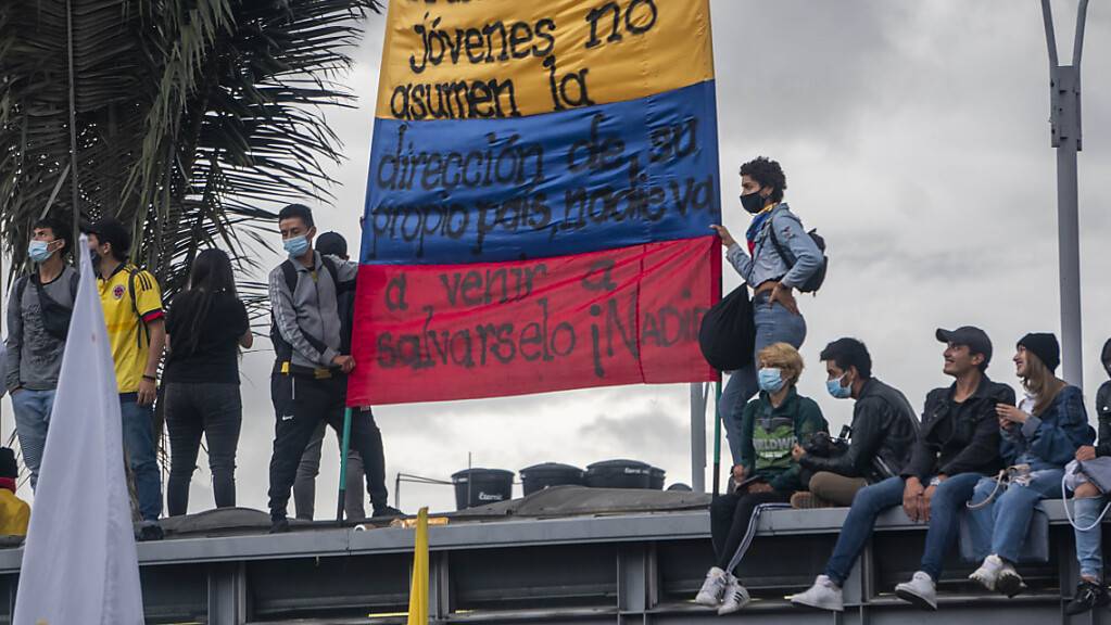 Menschen tragen eine kolumbianische Flagge, auf der geschrieben steht: «Wenn ihr jungen Leute nicht die Führung eures eigenen Landes übernehmt, wird niemand kommen, um euch zu retten, niemand».