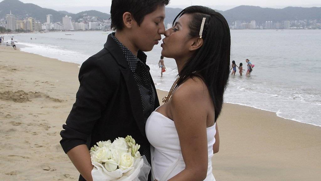 Ein gleichgeschlechtliches Paar küsst sich bei einer Gruppenhochzeit am Strand von Acapulco in Mexiko.