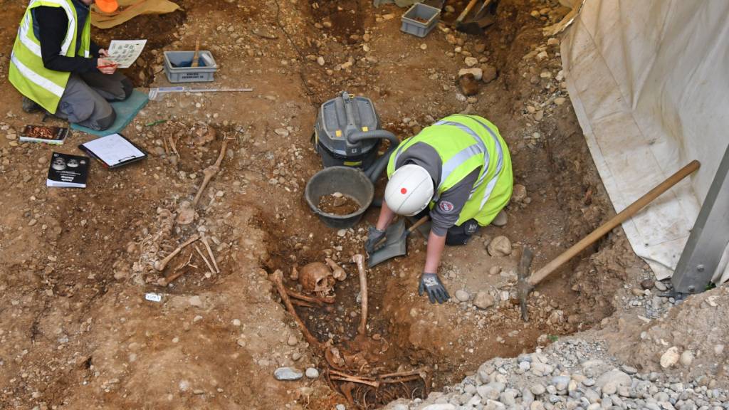 Archäologinnen haben die Skelette von zwei Personen freigelegt, deren Köpfe zwischen den Beinen liegen.