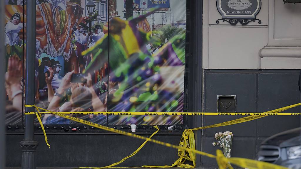 Ein Mann hat einen Blumenstrauß an der Kreuzung von Bourbon Street und Canal Street gelegt, während Ermittlungen laufen, nachdem ein Pickup-Truck am frühen Neujahrstag in eine Menge Feiernder gefahren wurde. Foto: Matthew Hinton/AP/dpa
