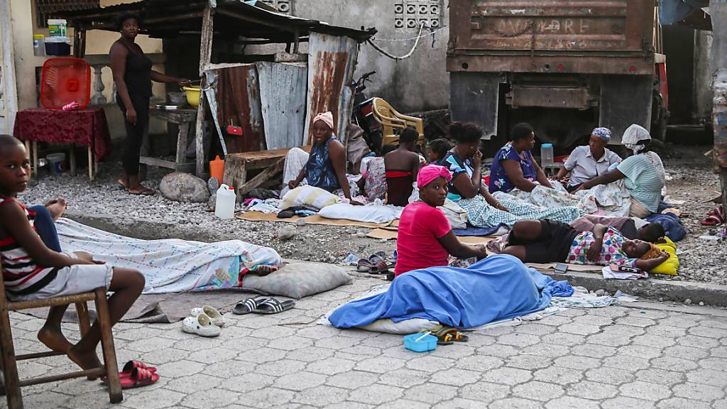 Einheimische, die die Nacht in Schlafsäcken im Freien verbracht haben, wachen am Tag nach einem Erdbeben auf. Das Erdbeben der Stärke 7,2 hat Haiti am 14.08.2021 erschüttert. Foto: Joseph Odelyn/AP/dpa
