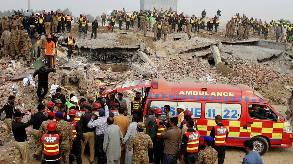 Pakistanische Soldaten, Rettungskräfte und Freiwillige suchen in den Trümmern der eingestürzten Fabrik nach Verschütteten.