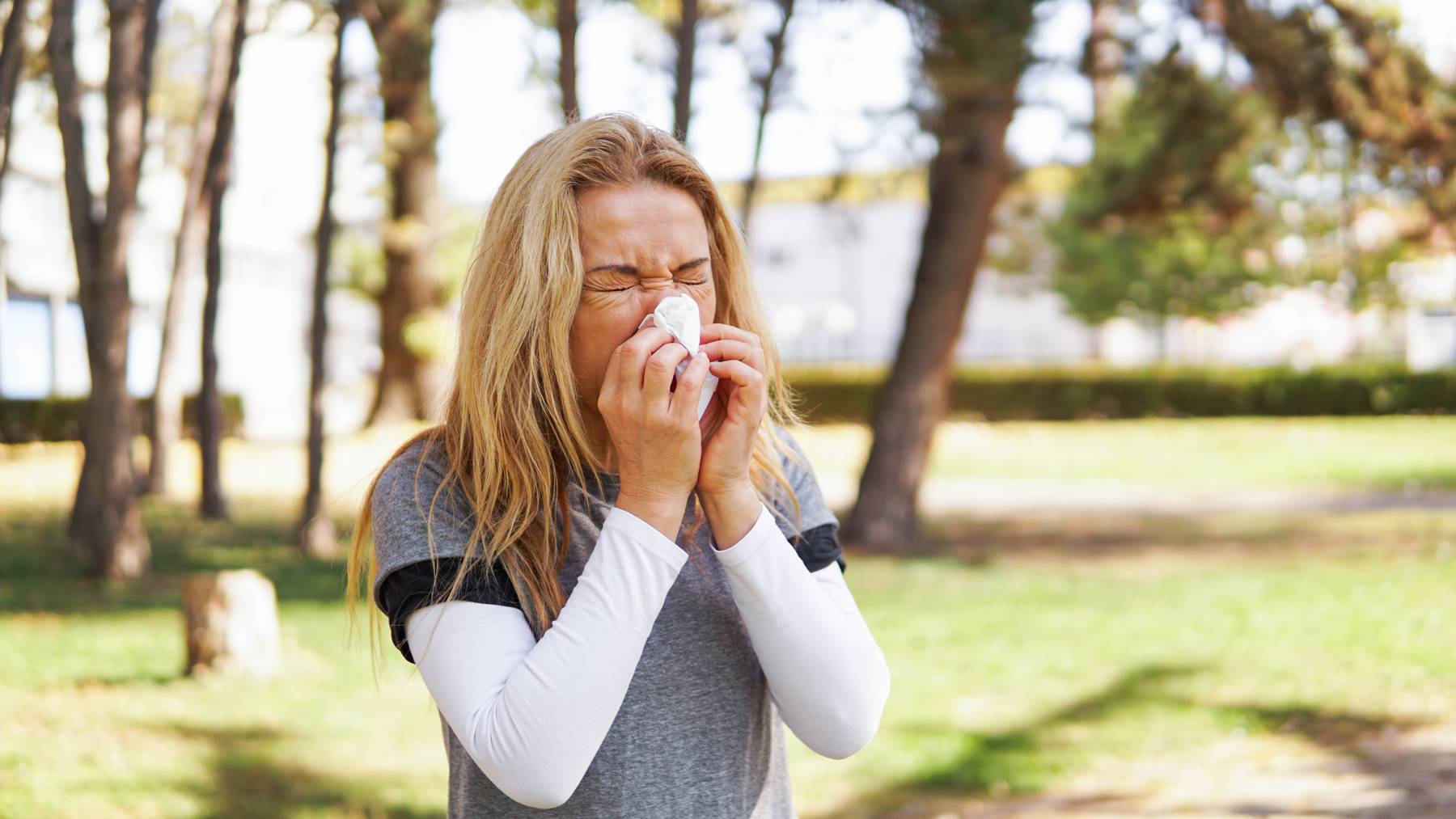 Frau leidet an Pollenallergie und putzt sich die Nase