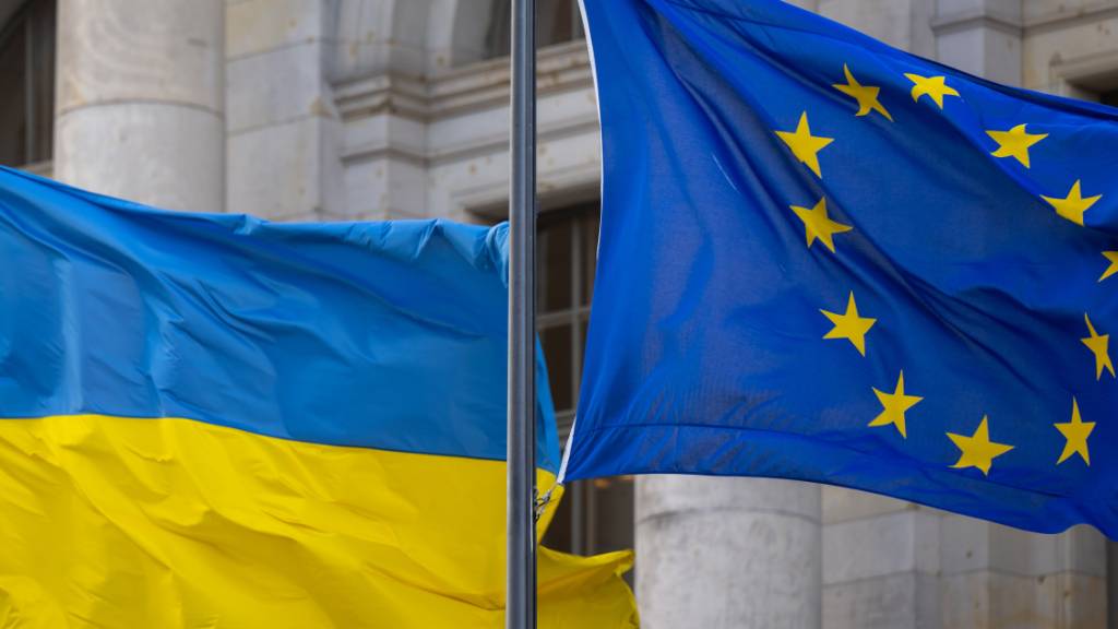 ARCHIV - Die Nationalflagge der Ukraine und die Flagge der EU wehen im Wind. Foto: Monika Skolimowska/dpa