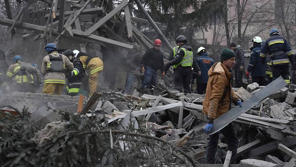 Menschen räumen die Trümmer am Ort eines russischen Luftangriffs. Russland hat die benachbarte Ukraine in der Nacht und am Freitagmorgen erneut massiv mit Drohnen und Marschflugkörpern angegriffen. Foto: Andriy Andriyenko/AP/dpa