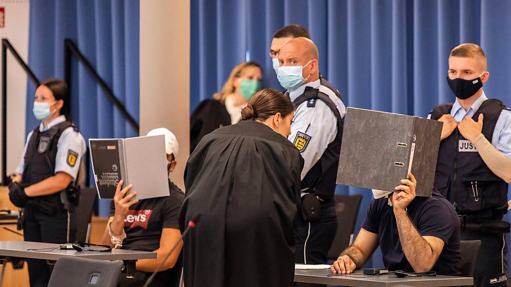 dpatopbilder - Zwei Angeklagte halten während des Prozesses in Freiburg Mappen als Sichtschutz vor ihre Gesichter. Foto: Philipp von Ditfurth/dpa - ACHTUNG: Person(en) wurde(n) aus rechtlichen Gründen gepixelt