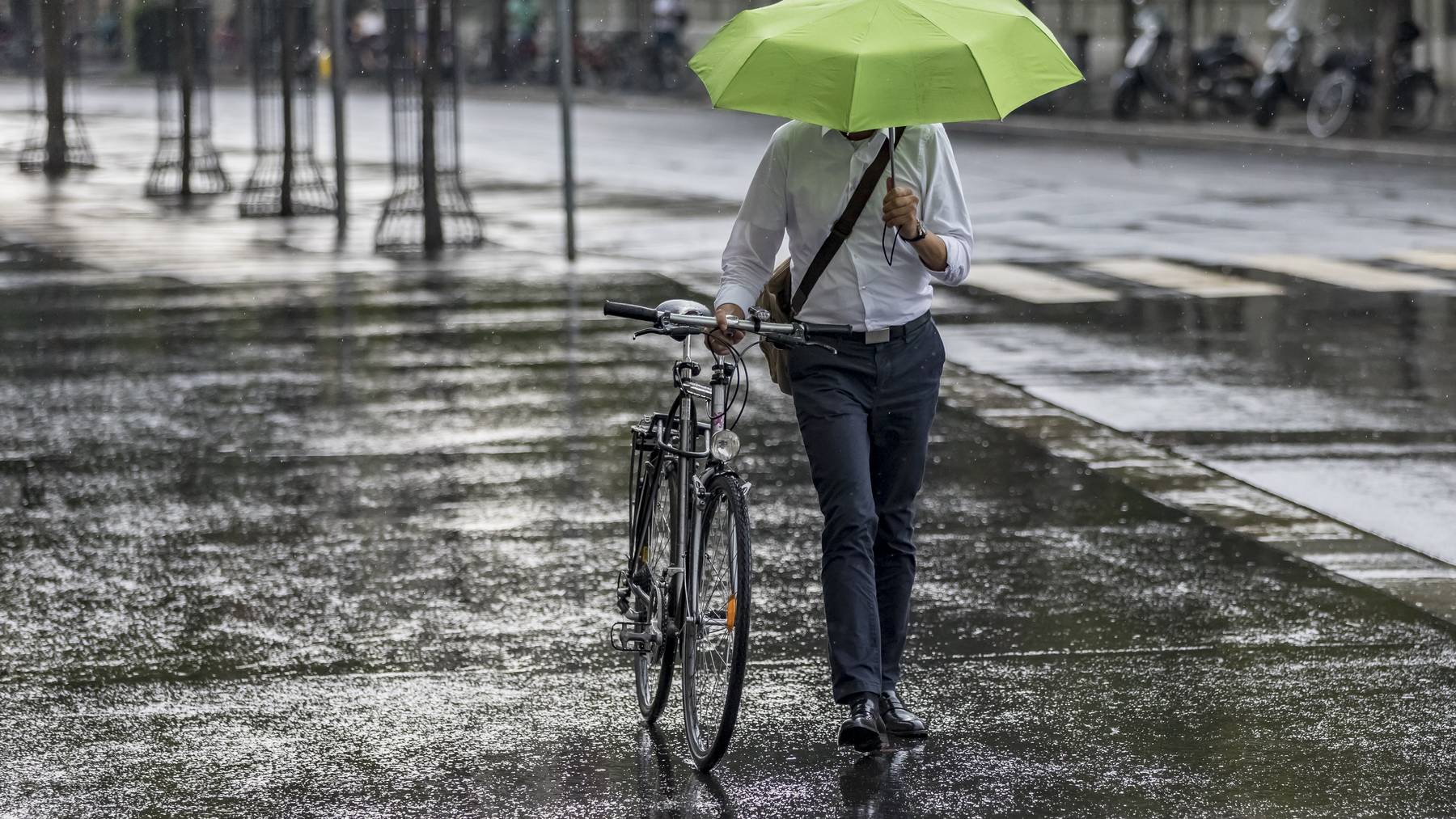 Ein Mann mit einem Schirm läuft im Regen in Bern. (Archivbild)