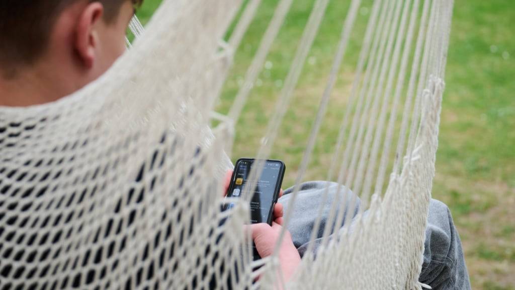 ARCHIV - Ein Junge guckt auf sein Smartphone, während er in einer Hängeschaukel in einem Garten sitzt. Foto: Annette Riedl/dpa/Symbolbild