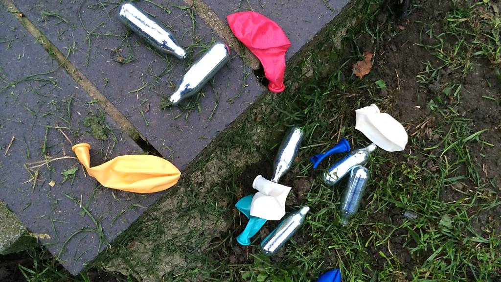 ARCHIV - Lachgas-Kartuschen und Luftballons liegen in einem Park im Londoner Stadtteil Shoreditch. Die britische Regierung will den Konsum von Lachgas eindämmen - zum Jahresende soll die Substanz als Droge verboten werden. Foto: Teresa Dapp/dpa