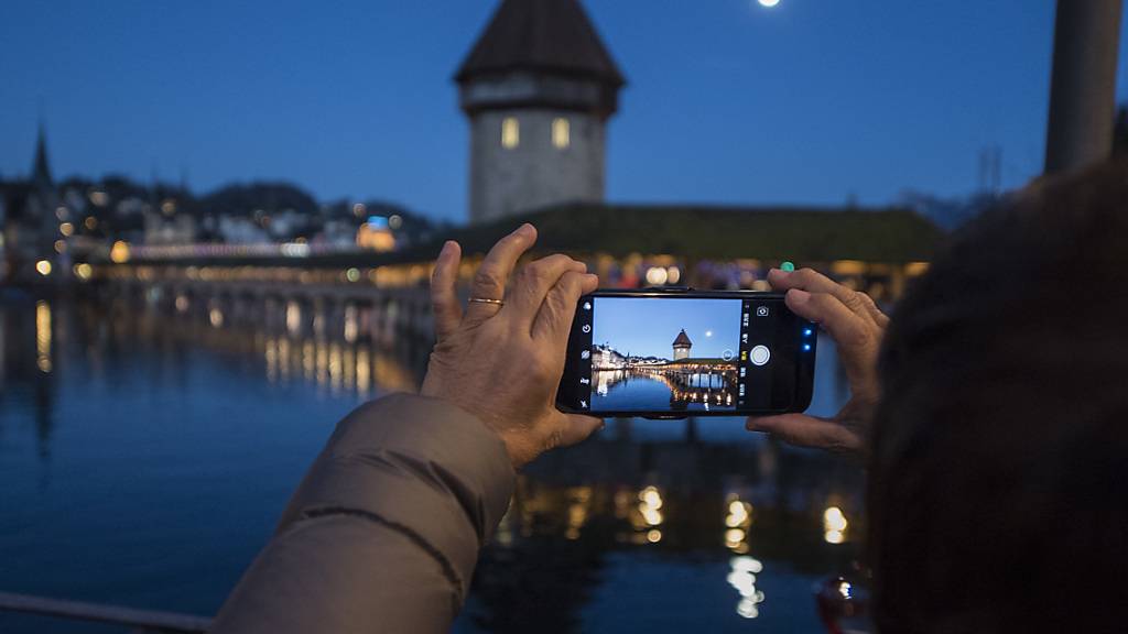 Eine asiatische Touristin macht ein Foto der Kapellbruecke mit dem Smartphone in der Altstadt von Luzern. (Archivbild)