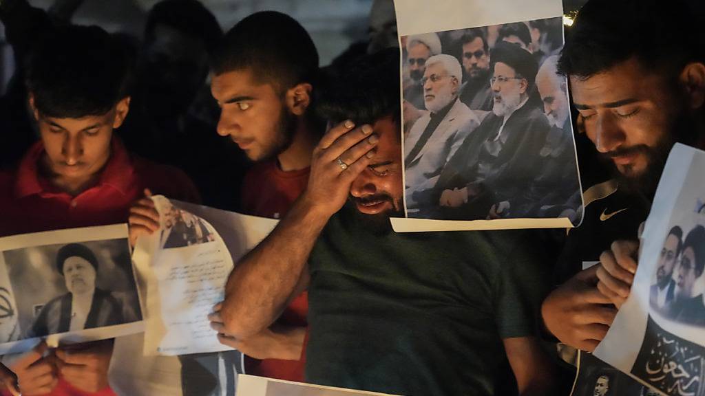 dpatopbilder - Ein schiitischer Muslim weint, während er Fotos des iranischen Präsidenten Ebrahim Raisi und anderer führender Persönlichkeiten während einer Mahnwache hält. Foto: Mukhtar Khan/AP