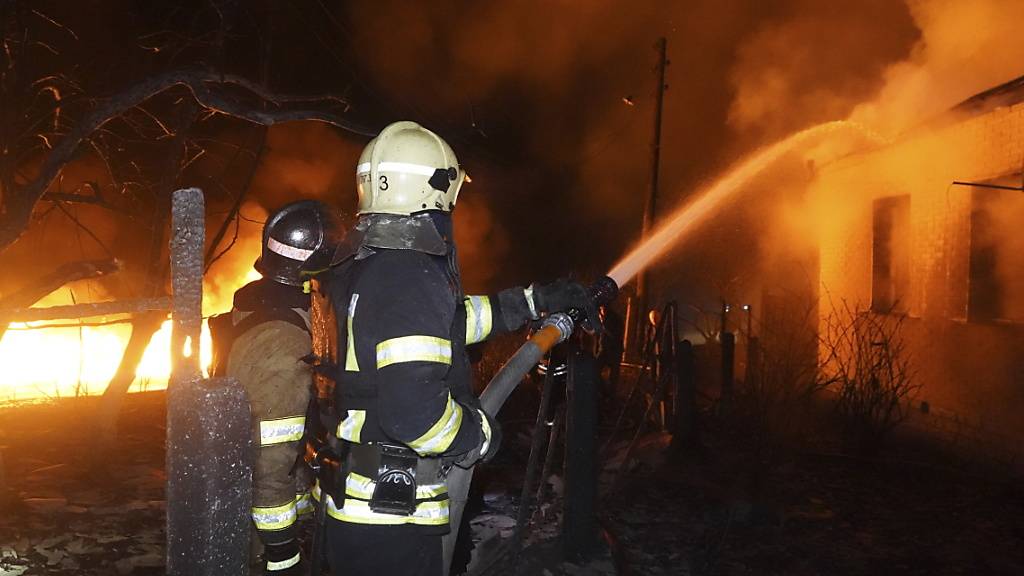 Feuerwehrleute löschen ein Feuer nach einem russischen Angriff auf ein Wohnviertel in Charkiw, Ukraine. Foto: Andrii Marienko/AP/dpa