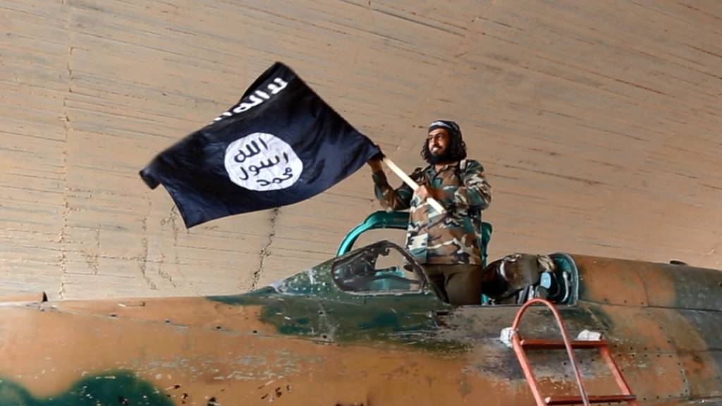 Ein Kämpfer der Terrormiliz Islamischer Staat schwenkt eine IS-Fahne in Syrien. (Archivbild)