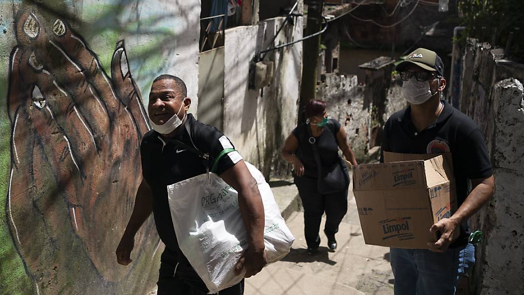 Freiwillige bringen Pakete mit Seife und Waschmittel in einen Slum in Rio de Janeiro.
