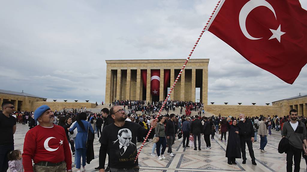 Ein Mann schwenkt eine türkische Nationalfahne, während Tausende das Mausoleum von Mustafa Kemal Atatürk besuchen. Die Vereinten Nationen verwenden auf Wunsch der Türkei ab sofort «Türkiye» anstelle der bisherigen englischen Landesbezeichnung «Turkey». Foto: Burhan Ozbilici/AP/dpa