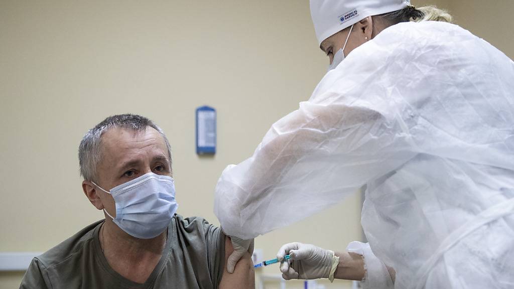Eine medizinische Mitarbeiterin verabreicht einem Mann den Corona-Impfstoff Sputnik V. Foto: Pavel Golovkin/AP/dpa