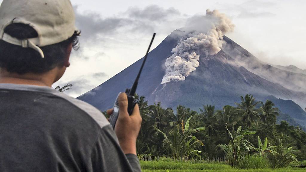 Ein freiwilliger Helfer benutzt sein Walkie-Talkie, während er den Vulkan Mount Merapi während einer Eruption überwacht. Der Vulkan Merapi ist erneut ausgebrochen und spukte mehrere Stunden glühende Asche und Gestein. Foto: Slamet Riyadi/AP/dpa