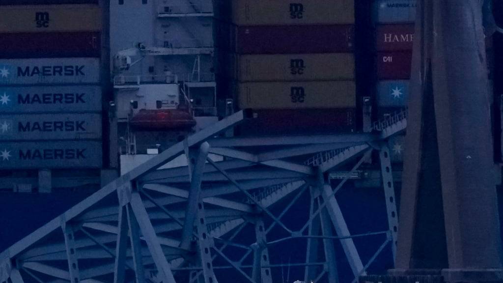 Ein Containerschiff liegt bei Einbruch der Dunkelheit am Wrack der Francis Scott Key Bridge. Foto: Matt Rourke/AP