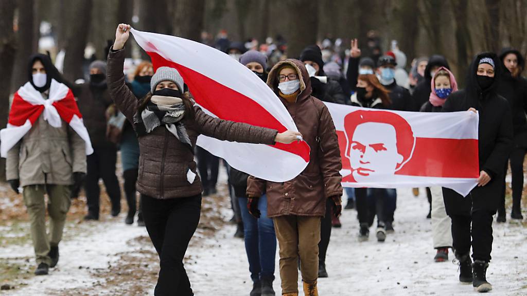 Demonstranten mit Mund-Nasen-Schutz tragen bei einer Kundgebung, auf der sie den Rücktritt von Machthaber Lukaschenko fordern, Fahnen in den Farben der früheren belarussischen Nationalflagge.