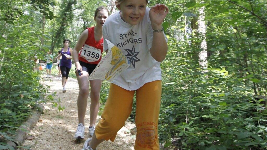 Hier halten sich die Zecken besonders gerne auf: Kinder an einem Orientierungslauf für Schüler und Schülerinnen im Wald. (Archivbild)