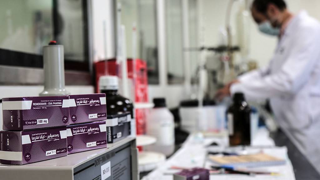 ARCHIV - Ein Mitarbeiter des ägyptischen Pharmaunternehmens «Eva Pharma» arbeitet an der Produktion des Wirkstoffs Remdesivir, einem antiviralen Breitspektrum-Medikament, während Packungen des Medikaments neben ihm liegen. Foto: Fadel Dawood/dpa