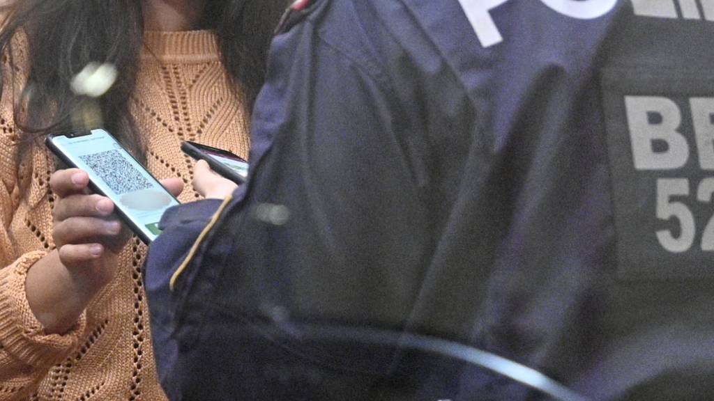 Die Polizei kontrolliert die Einhaltung der 2G-Regel in einem Wiener Cafe, während eine Frau ihren digitalem Impfnachweis auf ihrem Smartphone vorzeigt. Foto: Hans Punz/APA/dpa