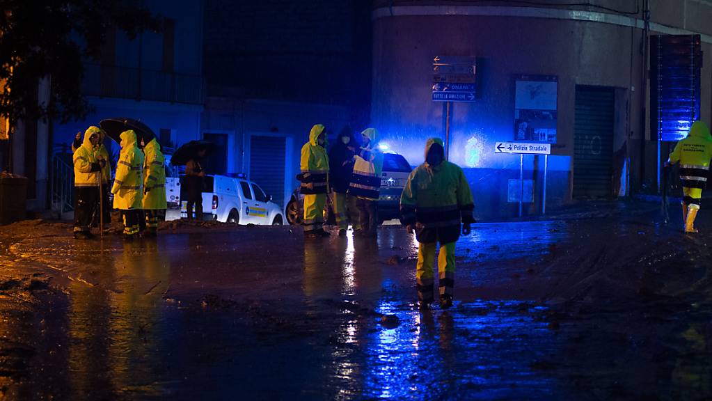 Rettungskräfte stehen an einer mit Schlamm überzogenen Straße. Foto: Alessandro Tocco/LaPresse via ZUMA Press/dpa