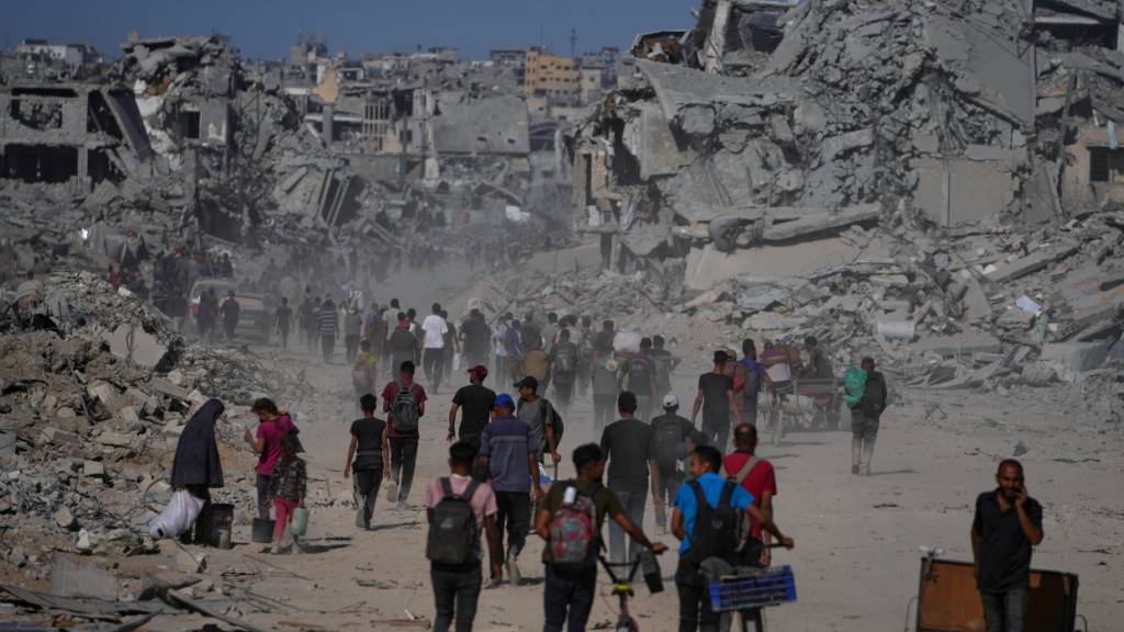 dpatopbilder - Palästinenser gehen an zerstörten Gebäuden vorbei, während sie in ihre Häuser im Zeitoun-Viertel von Gaza zurückkehren. Foto: Jehad Alshrafi/AP/dpa