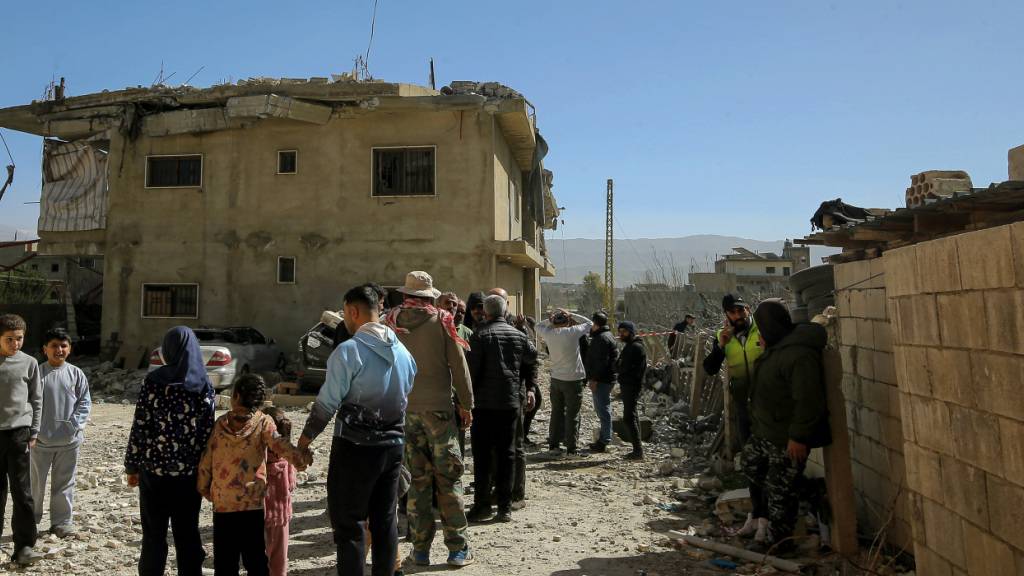Menschen versammeln sich an einem zerstörten Gebäude, das bei einem israelischen Luftangriff in dem Dorf Temnine in der Bekaa-Ebene getroffen wurde. Bei dem Angriff wurden zehn Menschen getötet, darunter acht Hisbollah-Kämpfer. Foto: Marwan Naamani/dpa