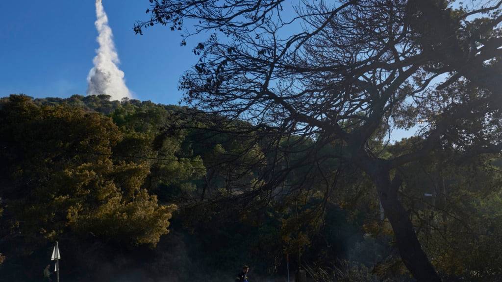 Ein Löschflugzeug wirft Wasser ab, während ein Waldbrand brennt und mehrere Häuser in der Gegend zerstört wurden. Foto: Petros Giannakouris/AP/dpa