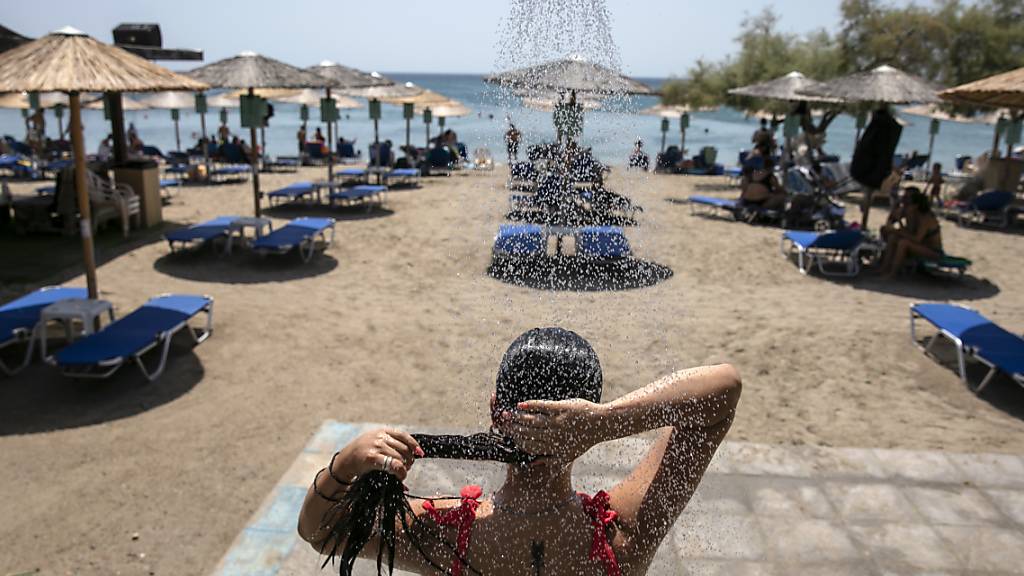 Eine Frau duscht an einem Strand des Dorfes Lagonissi, einige Kilometer südwestlich von Athen. Eine der schwersten Hitzewellen seit den 1980er Jahren ist über Südosteuropa hereingebrochen. In Teilen Griechenlands steigen die Temperaturen auf über 40 Grad Celsius. Foto: Yorgos Karahalis/AP/dpa